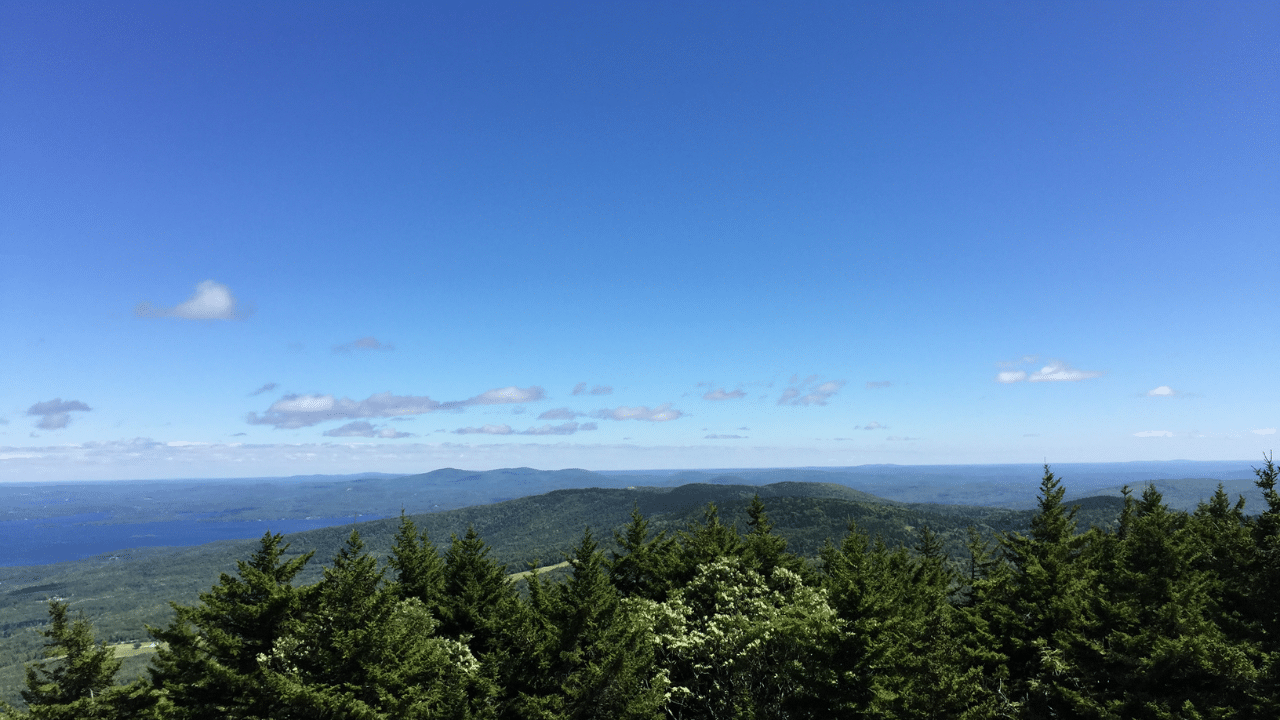 A breathtaking view from the top of the White Mountains Marathon reveals a stunning landscape of snowy peaks and a sparkling lake below.