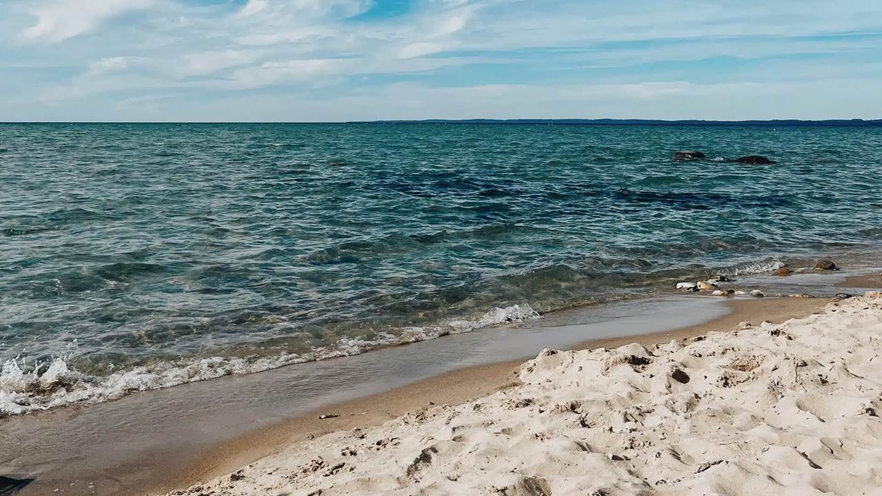 A beach with sand and water in the background near Traverse City.