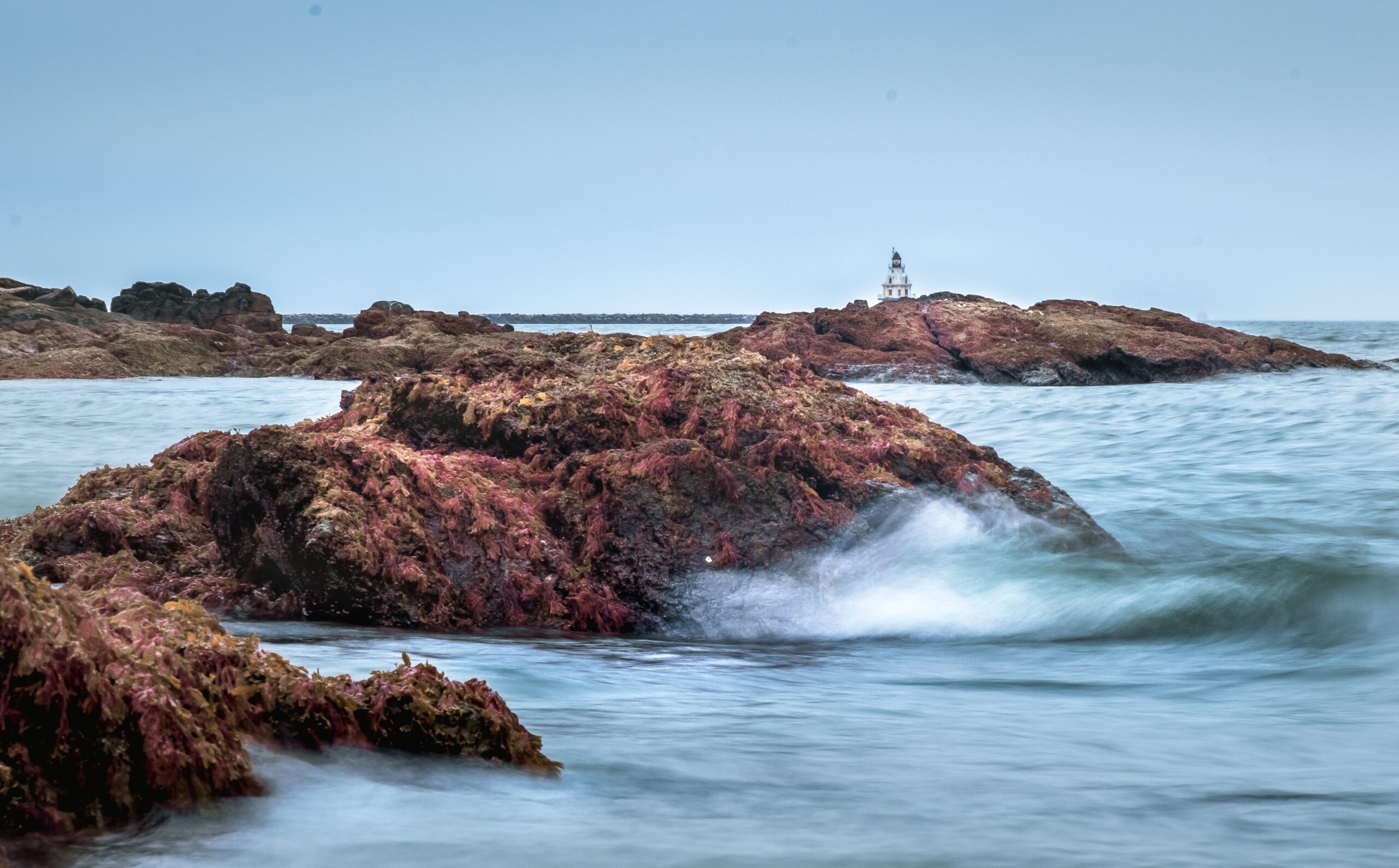 A lighthouse on a rock in the ocean.