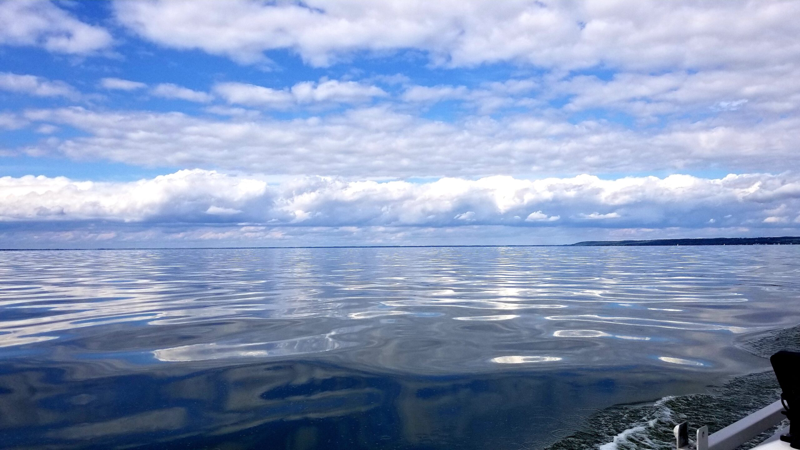 The view from the back of a boat on a calm body of water.