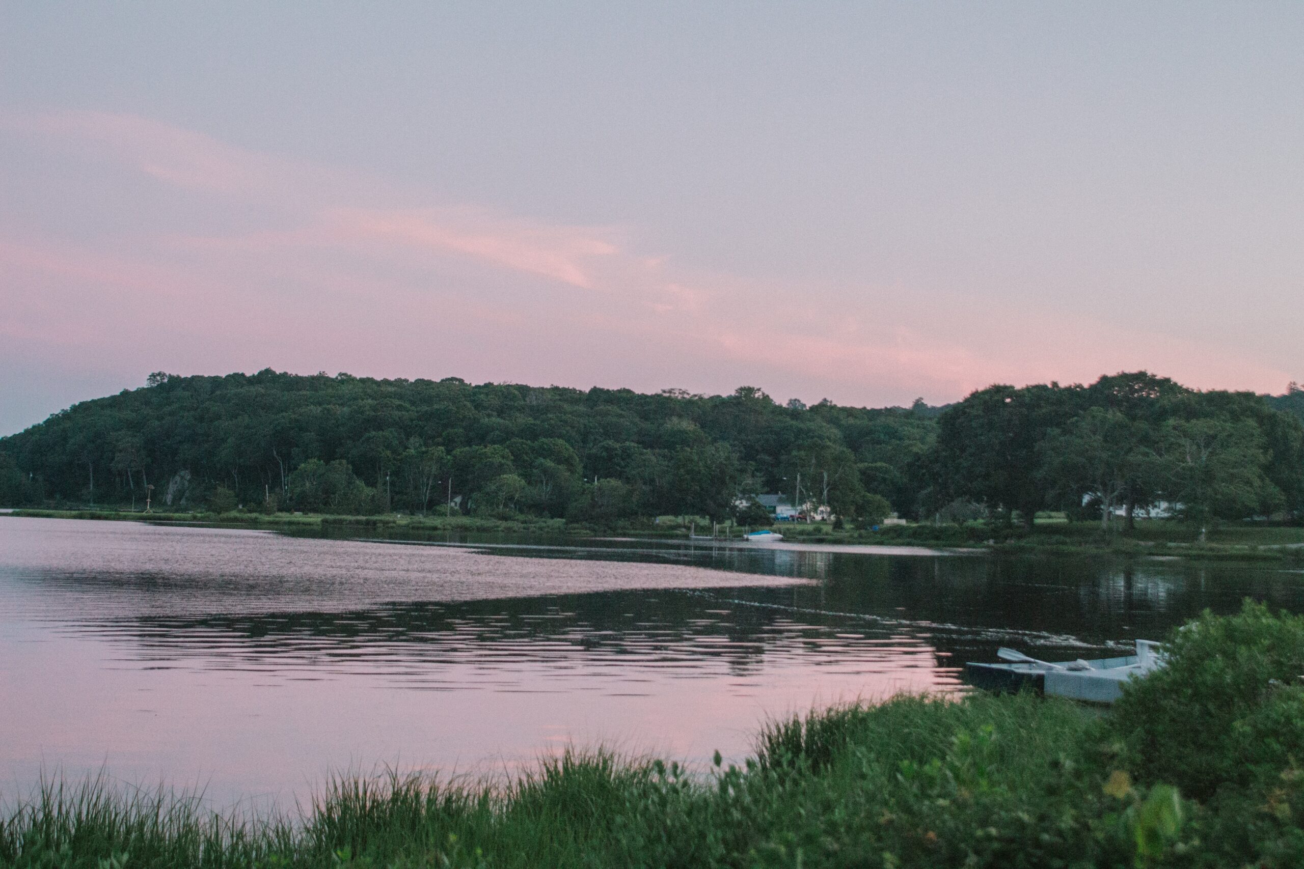 A boat docked on the shore of a lake at sunset.