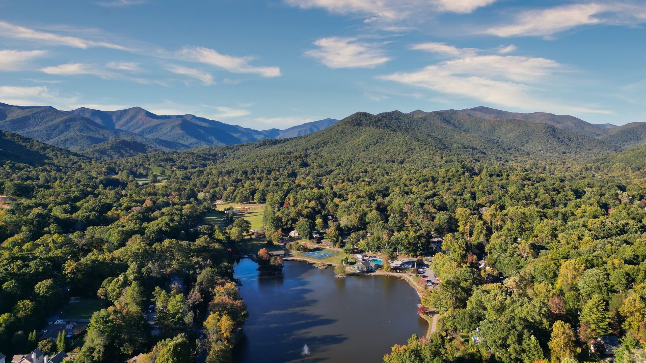 An aerial view of a lake surrounded by trees and mountains.