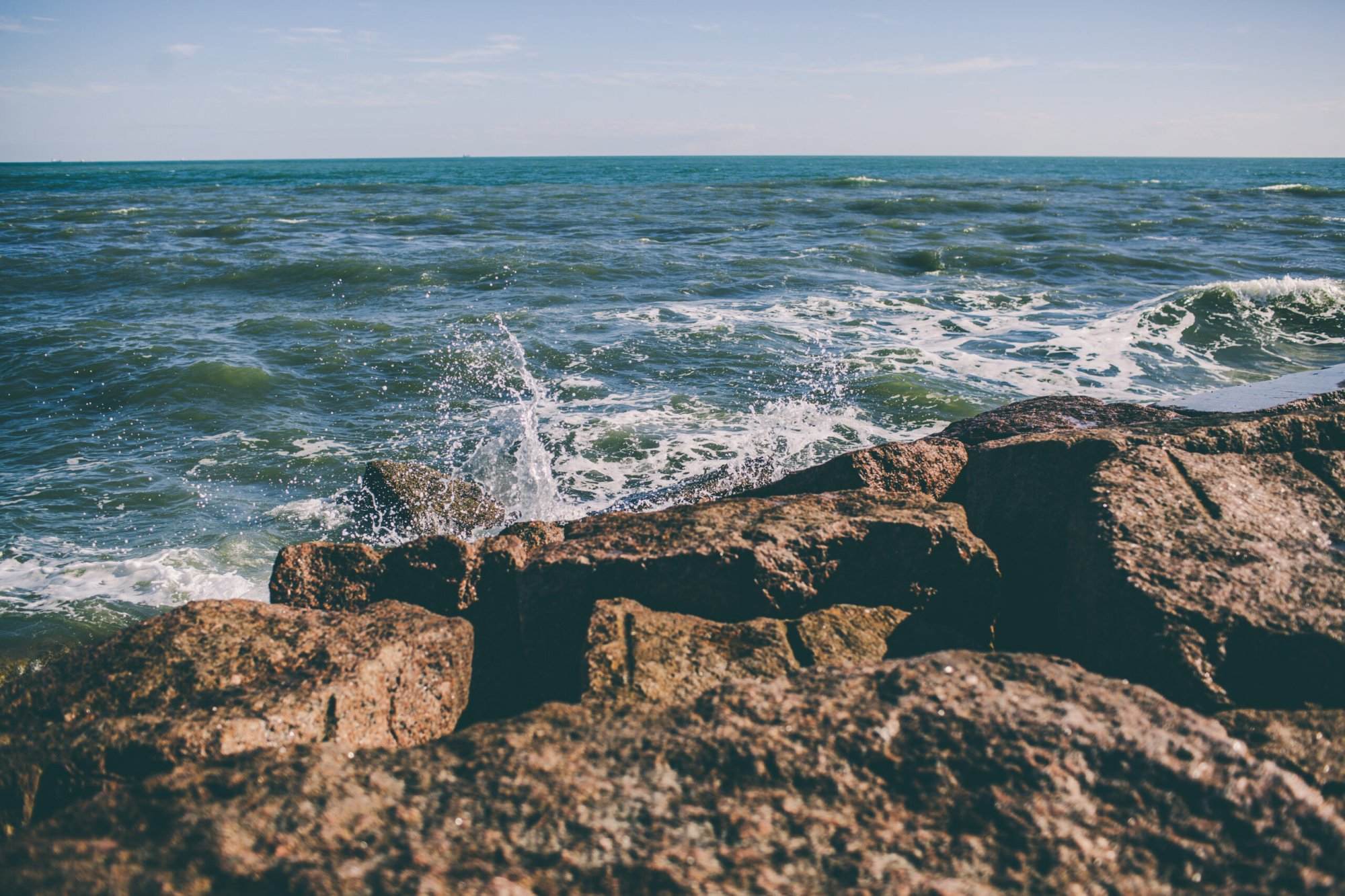 A rocky shore with waves crashing over rocks.