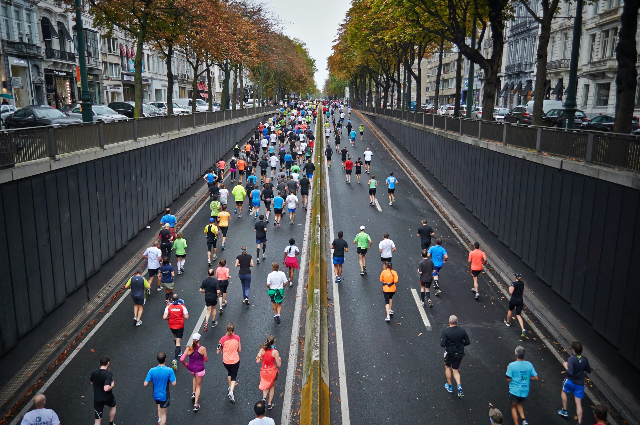 A group of people running down a street in a city.