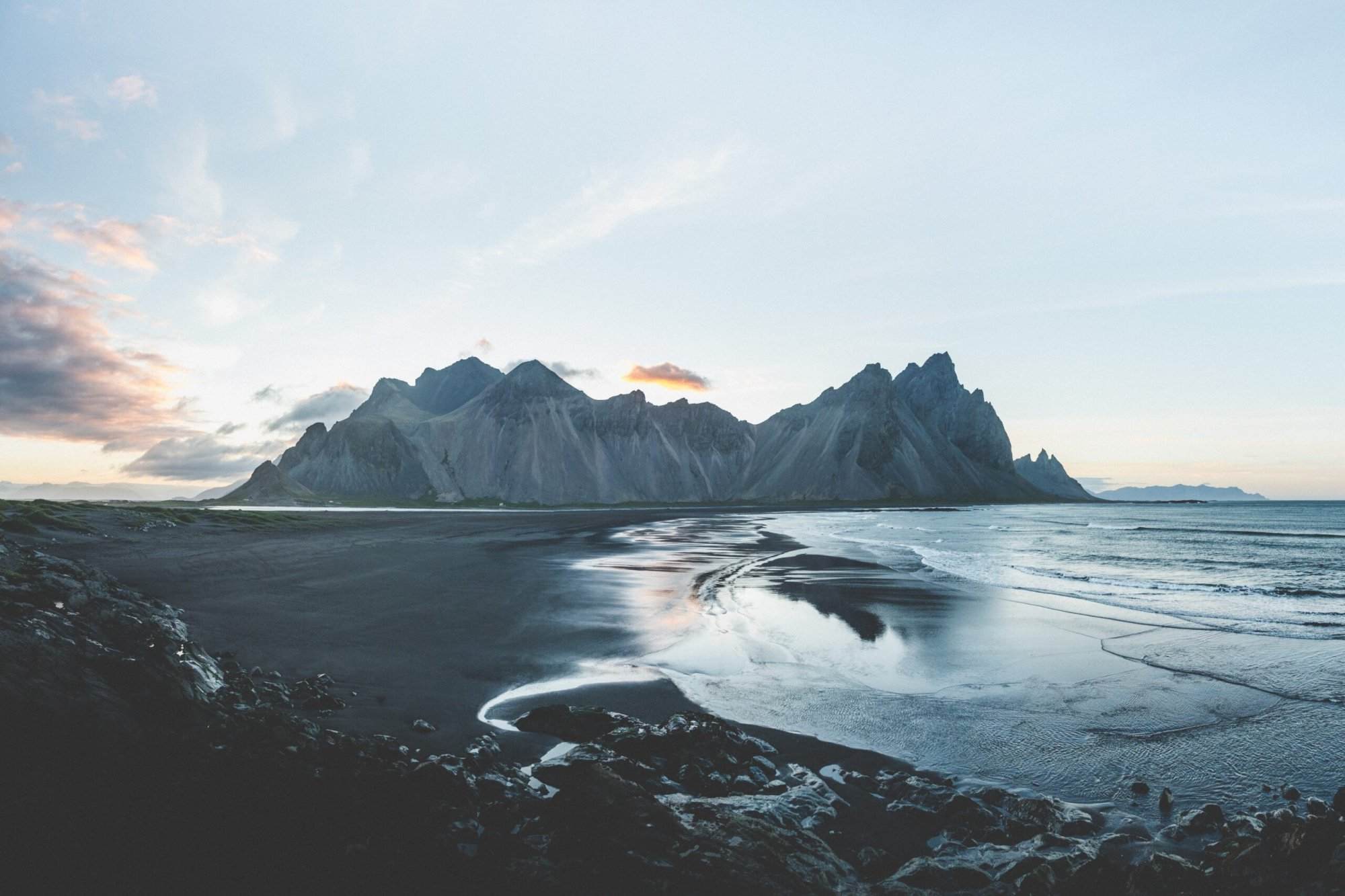 A black sand beach with mountains in the background.