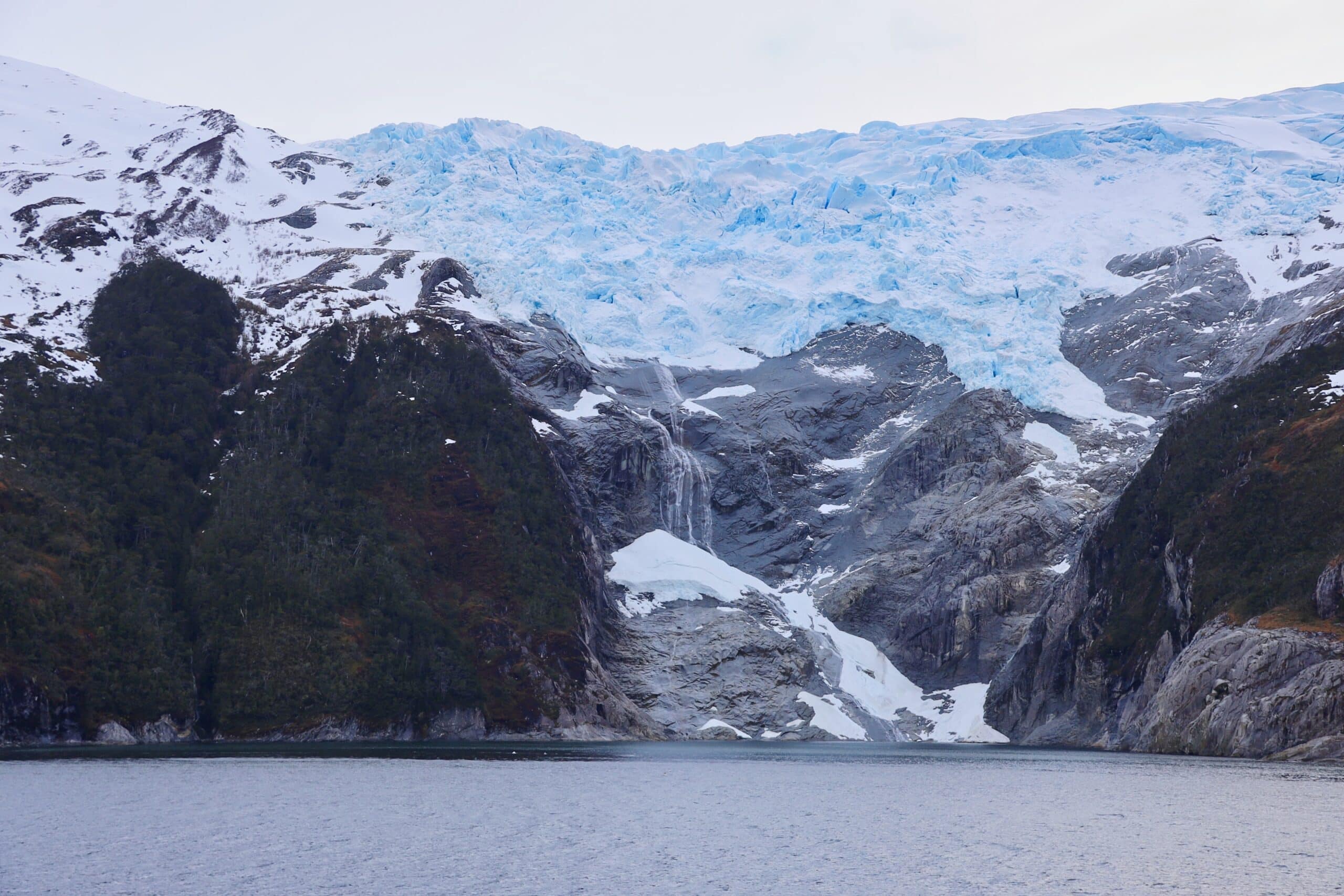 A glacier with a waterfall in front of it.