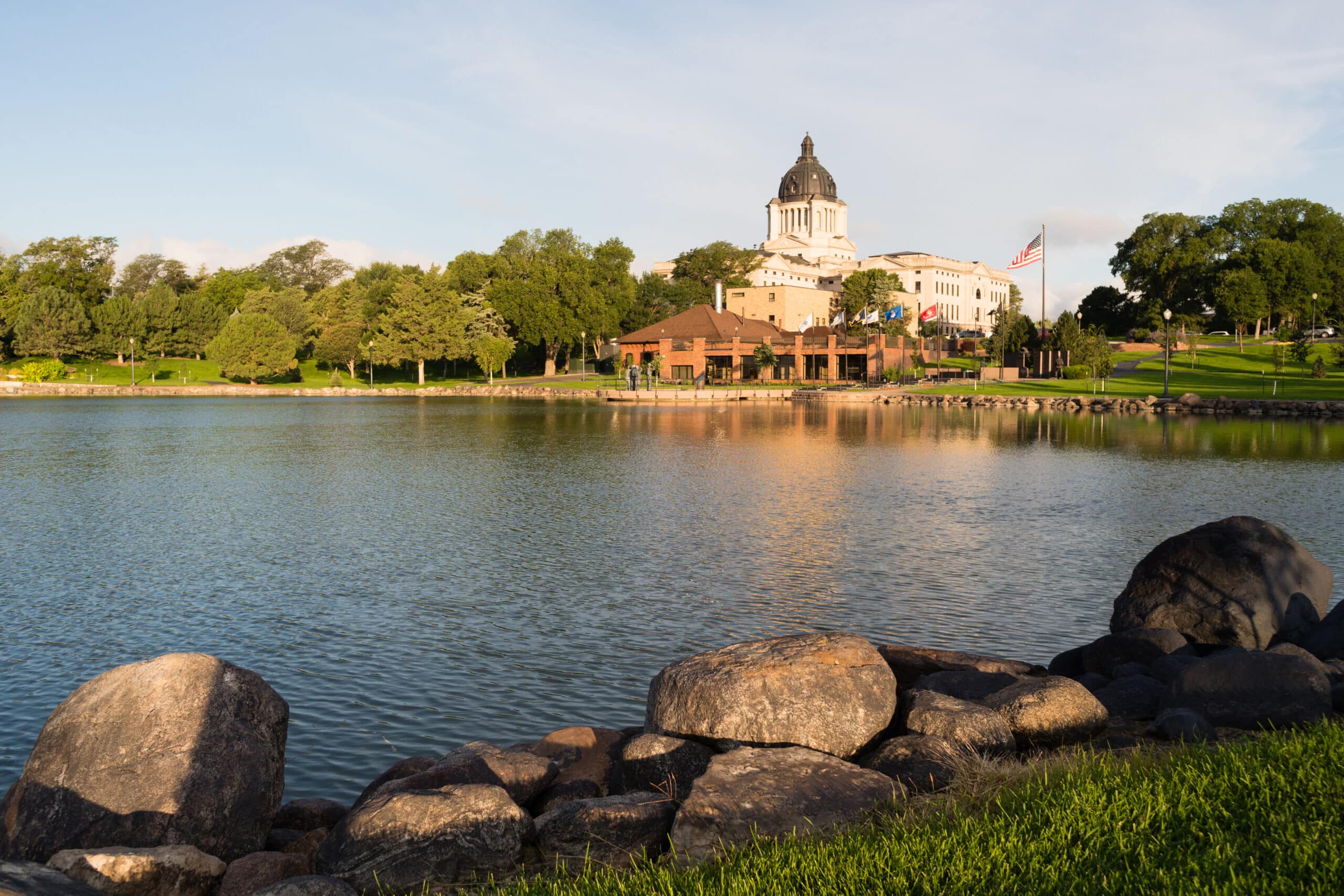 A lake with rocks and a clock tower in the background.