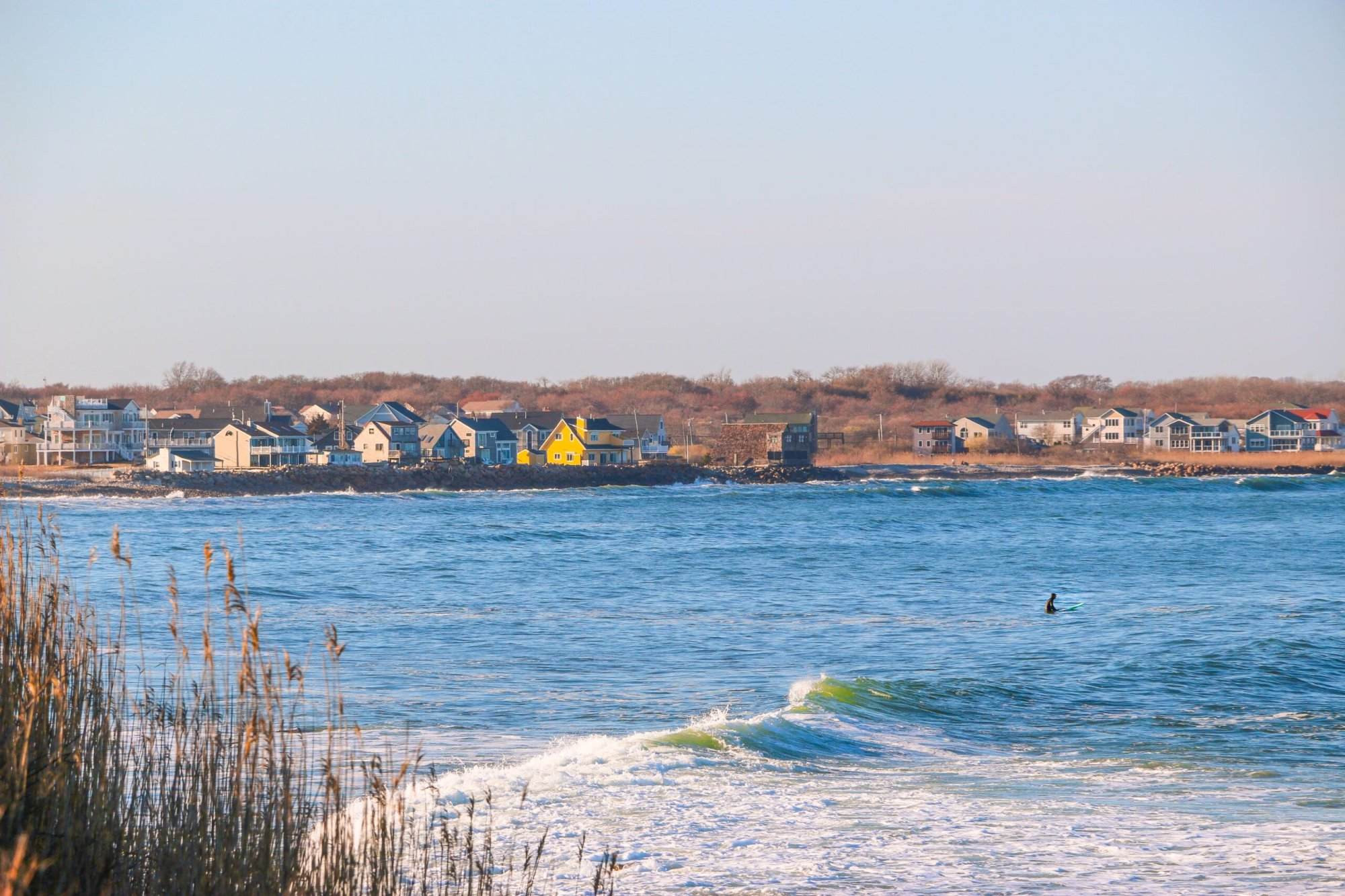 A surfer is riding the waves in front of a house.