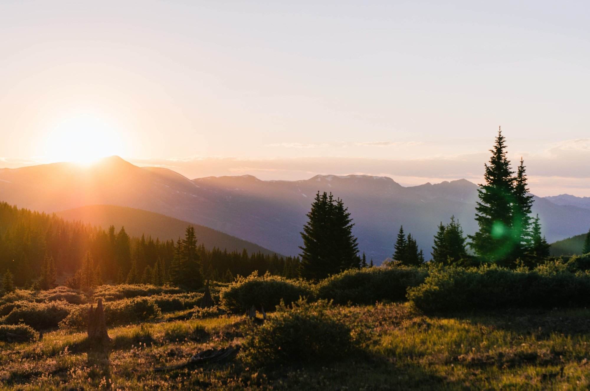 The sun is setting over a mountain range in colorado.