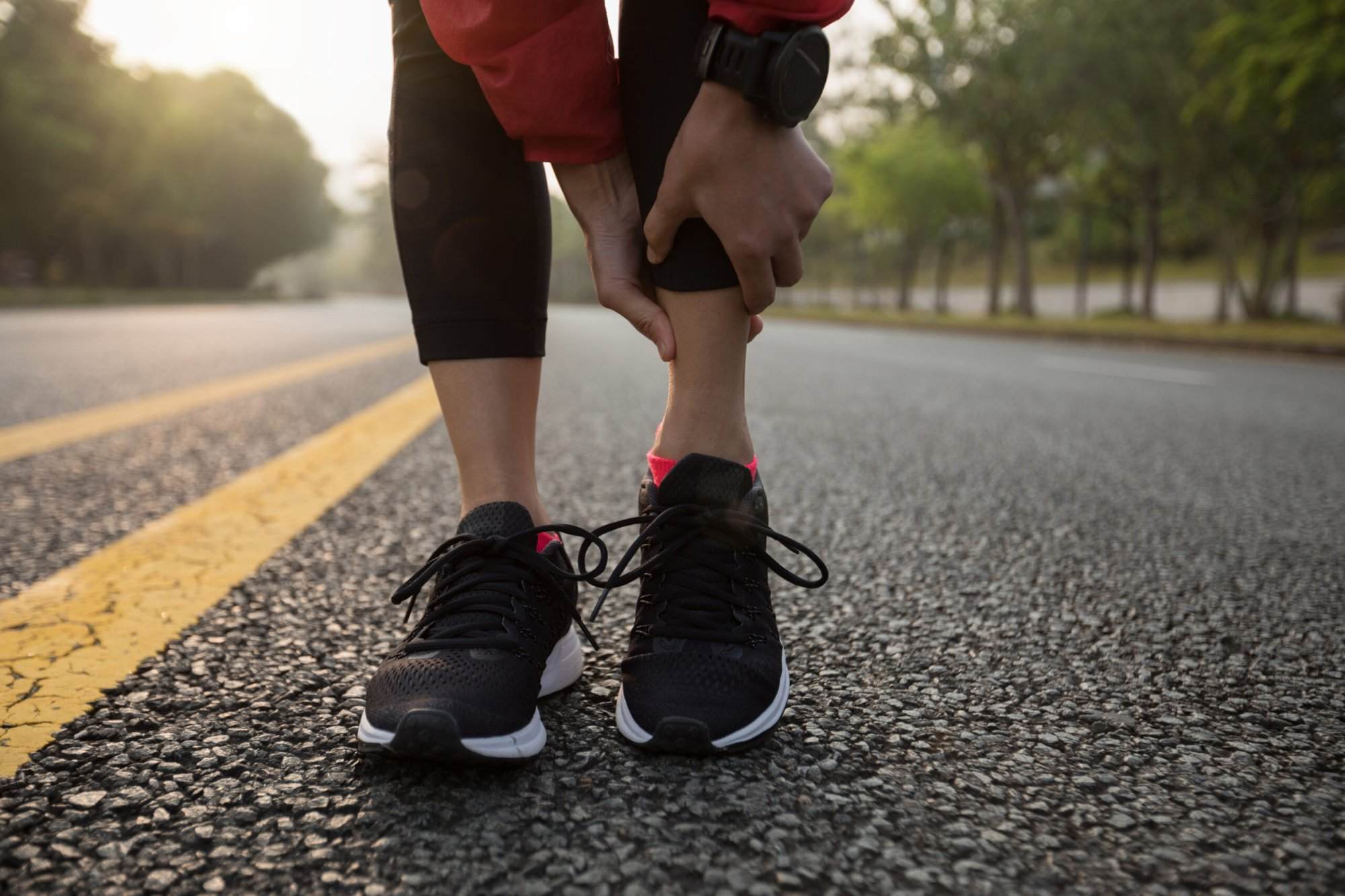 A woman is gradually increasing the intensity of her overtraining by tying her shoes on the road.