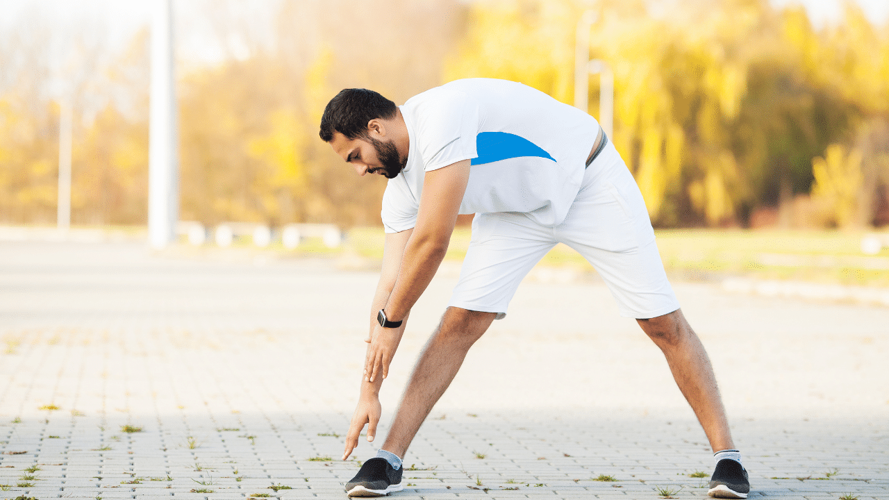 A man warming up his legs in the park.