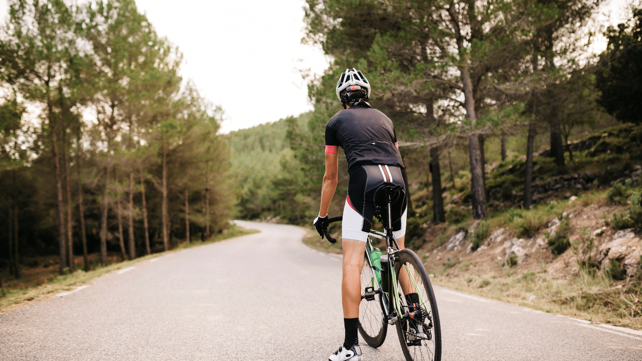 A man enjoying the benefits of cross training as he rides his bike down a country road.