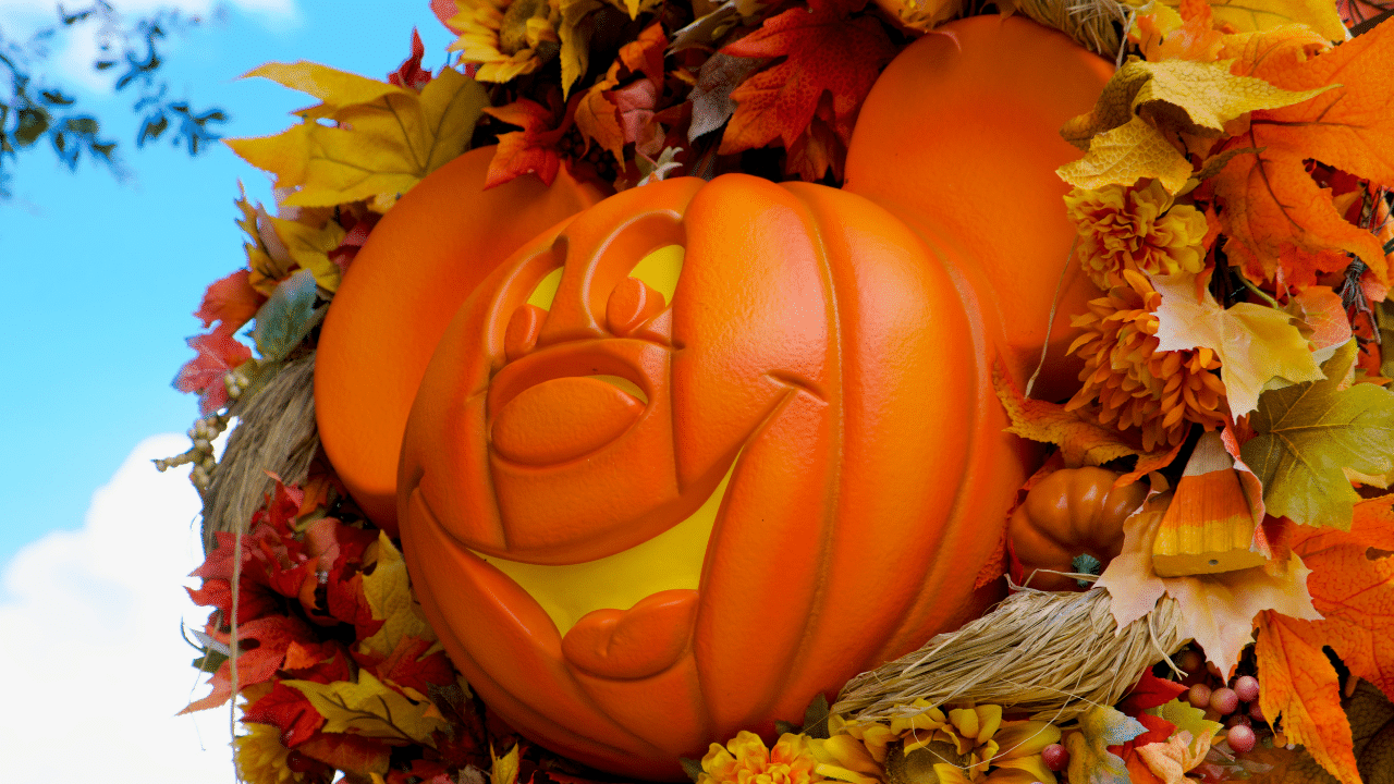 A Mickey mouse pumpkin adorned with a wreath of leaves.